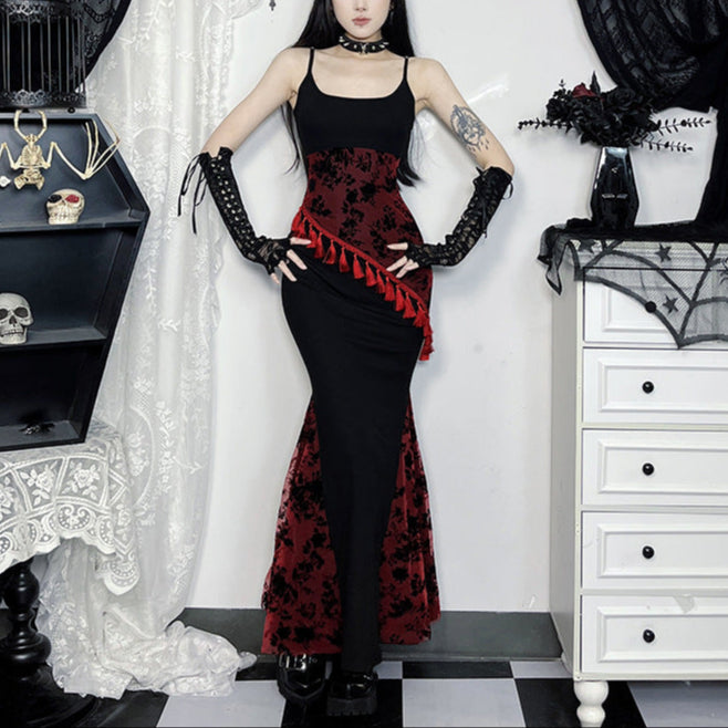 Person wearing a black and red gothic dress with matching gloves in a decorated room.