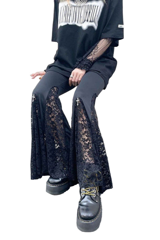 Person wearing black lace pants and platform shoes sitting on a wall.