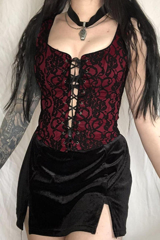 Person wearing a red lace corset and black skirt against a white background