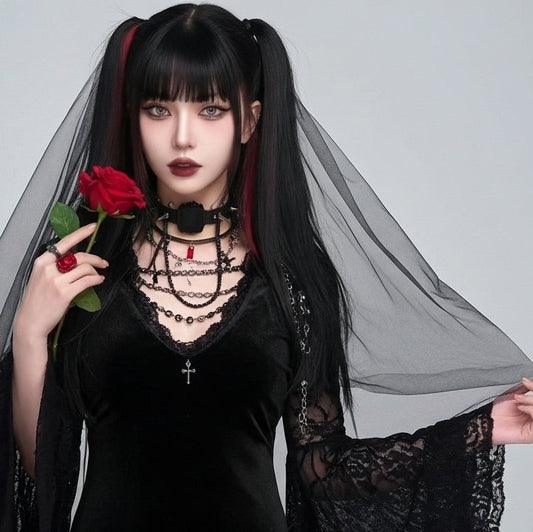 Person in gothic attire holding a red rose against a plain background