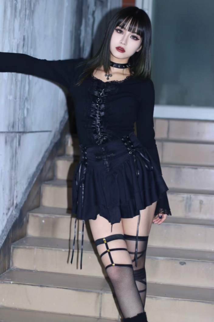 Person wearing a black outfit with lace-up details on stairs