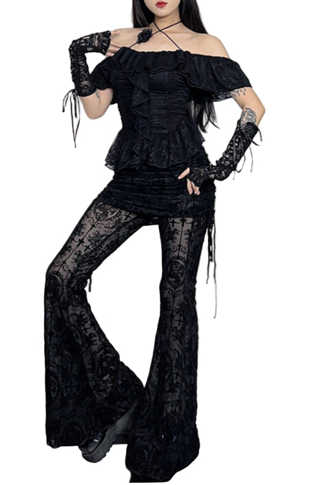 Woman in a black Halloween costume standing in a decorated room with pumpkins and bats.