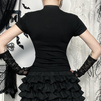 Person wearing a black dress with a ruffled skirt and black gloves in a decorative setting.