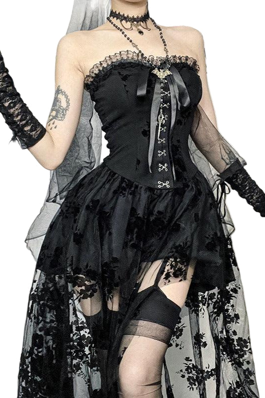 Person wearing a black lace dress with floral details in a gothic setting.