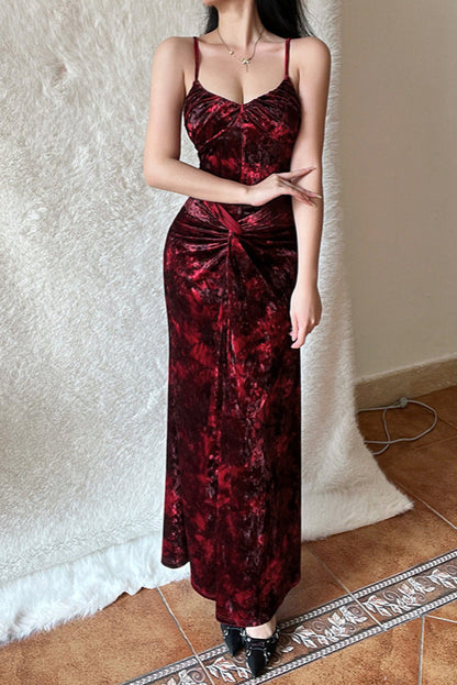 Person wearing a red velvet dress standing against a textured white wall.