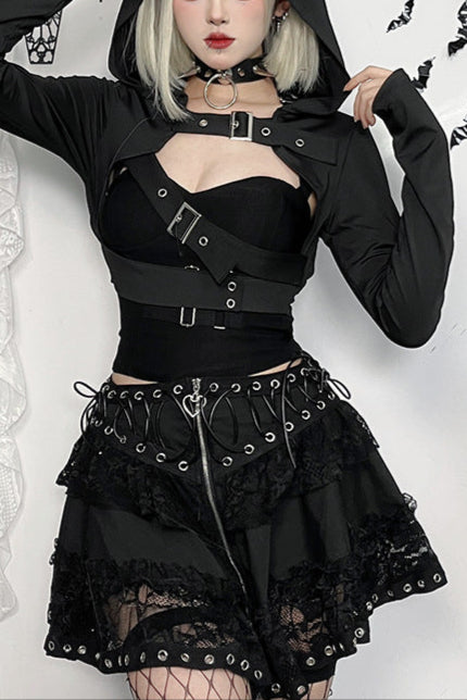 Person wearing a black gothic outfit with a hood in a decorative setting.
