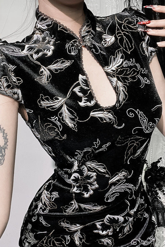 Black floral embroidered dress worn by a person with tattoos on their arms.