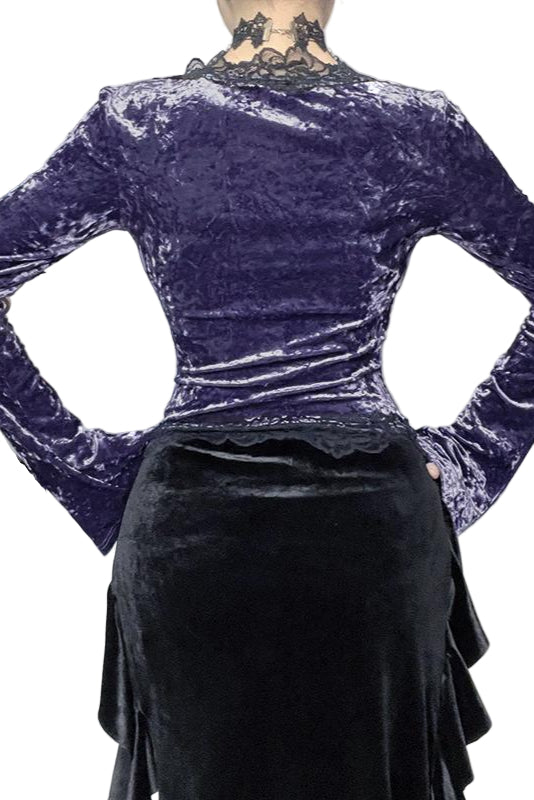Person wearing a purple velvet top and black skirt with a decorative background.