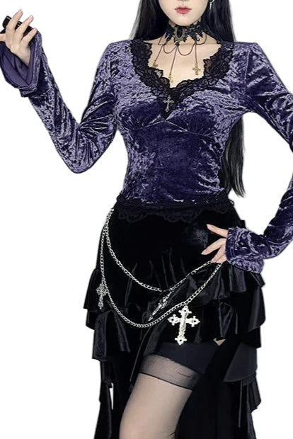 Person wearing a purple velvet top and black skirt with chains in a Halloween-themed setting.