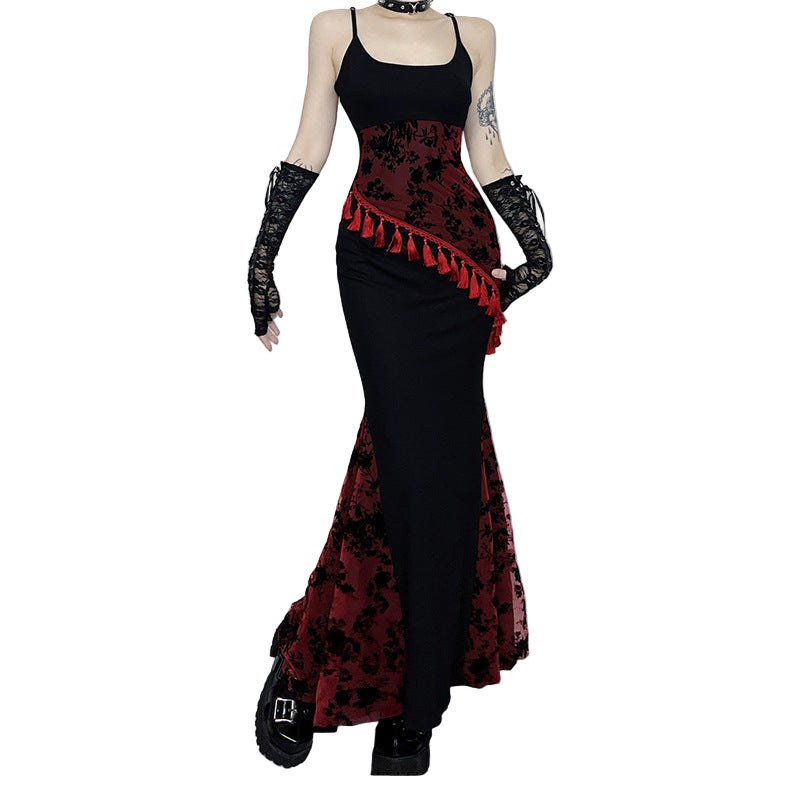 Person wearing a black and red floral dress with gloves in a room setting.