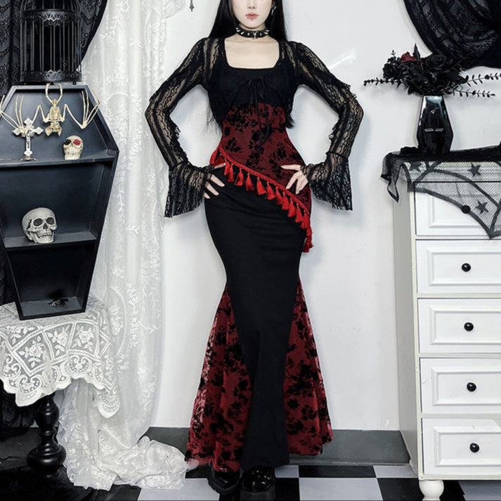 Person wearing a black and red gothic dress with lace sleeves in a decorative setting.