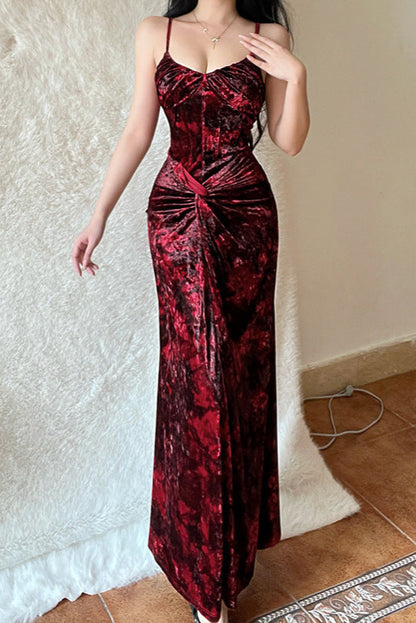 Woman wearing a red and black patterned dress against a plain wall.