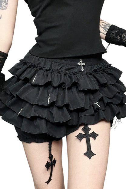 Person wearing a black ruffled skirt with cross designs, standing against a decorative background.