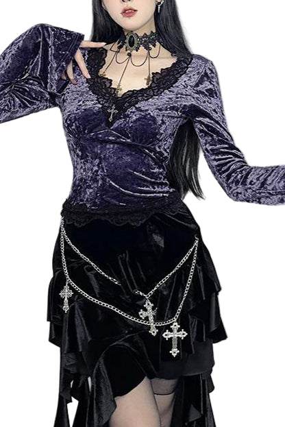 Person wearing a dark, gothic-style outfit with long sleeves and decorative chains.