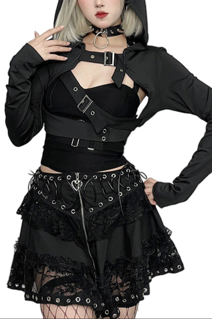 Person wearing a black gothic outfit with a hood and lace details in a decorative setting.