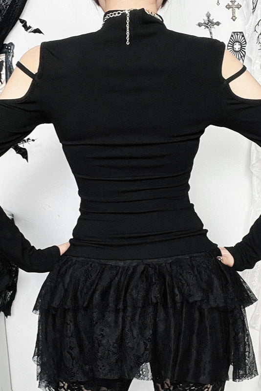 Black outfit with ruffled skirt and cut-out shoulders against a decorative background