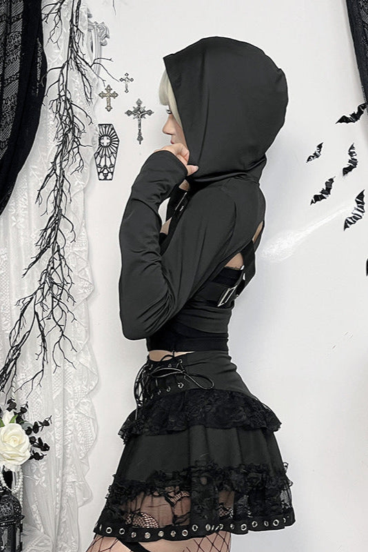 Person wearing a black hooded outfit with lace details in a gothic-style setting.