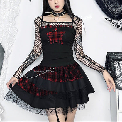 Woman wearing a black and red plaid dress with fishnet sleeves in a decorative setting.