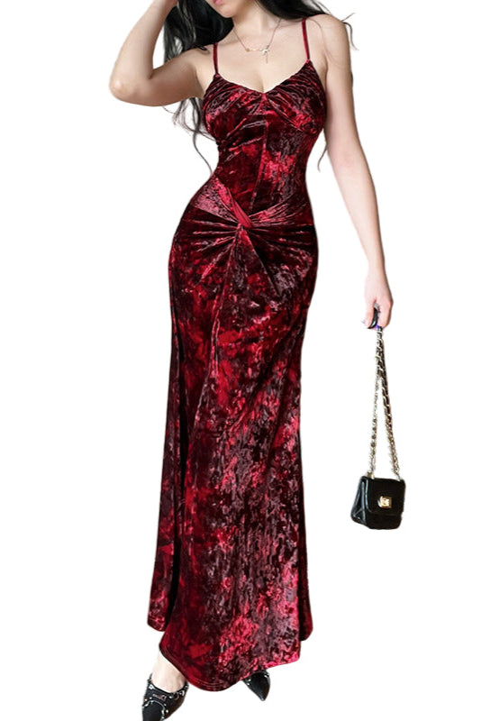 Woman wearing a red velvet dress holding a black handbag indoors.
