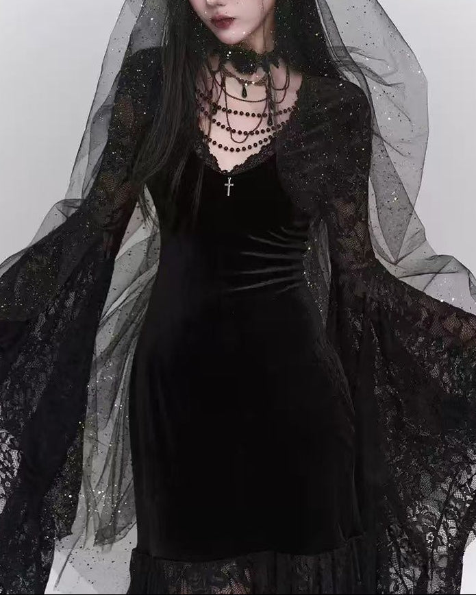 Person wearing a black dress with sheer overlay and layered necklaces against a white background