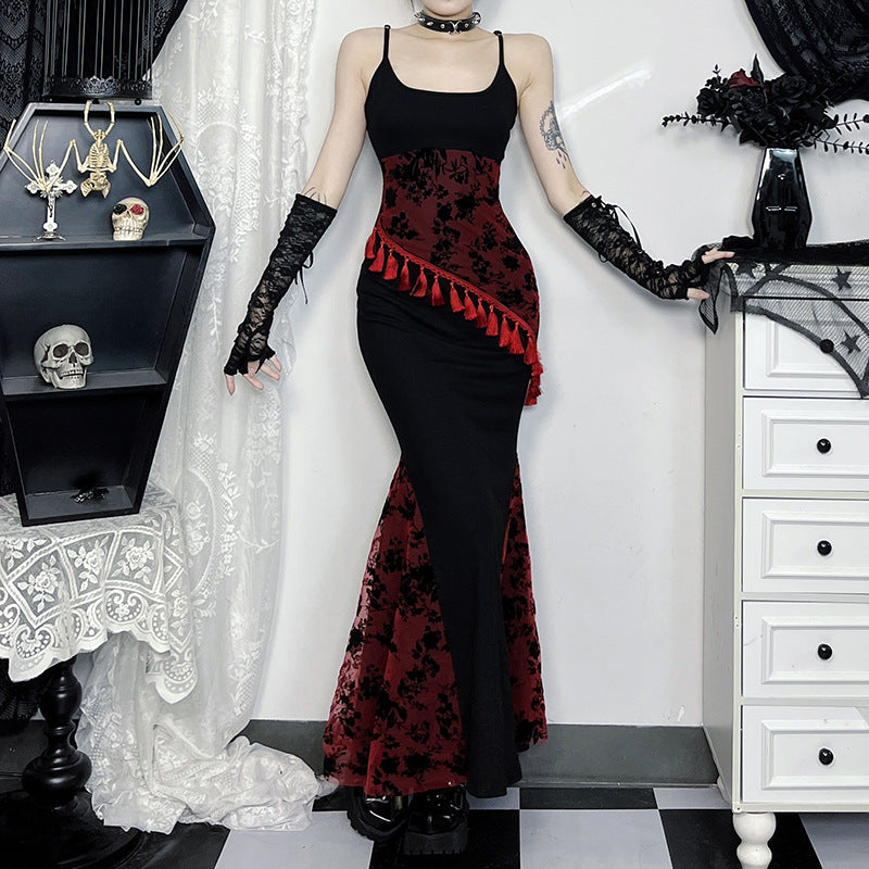 Person wearing a black and red gothic-style dress with lace gloves in a room.