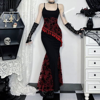 Person wearing a black and red gothic-style dress with lace gloves in a room.