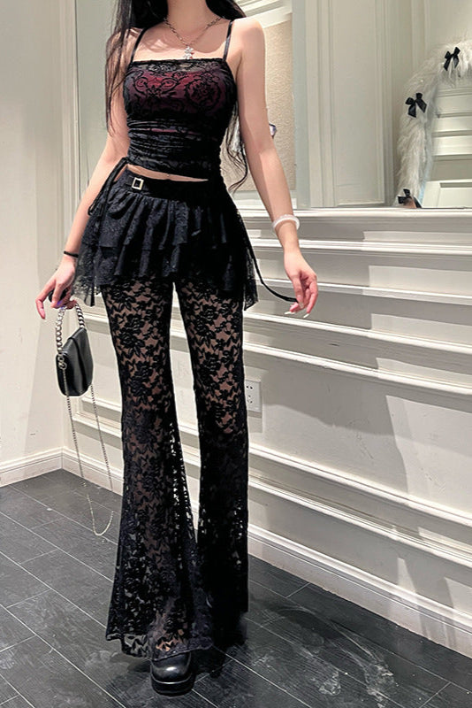 Person wearing a black lace outfit in a room with white walls and gray floor.
