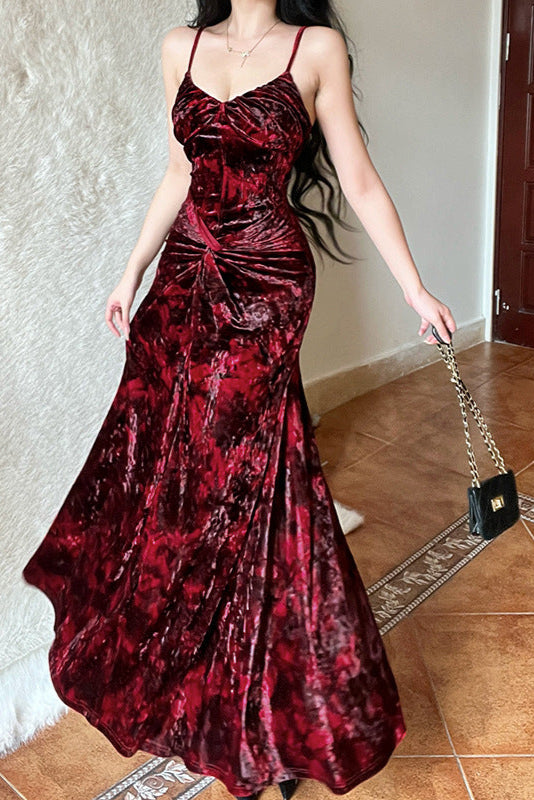 Woman wearing a red velvet dress holding a black handbag indoors.