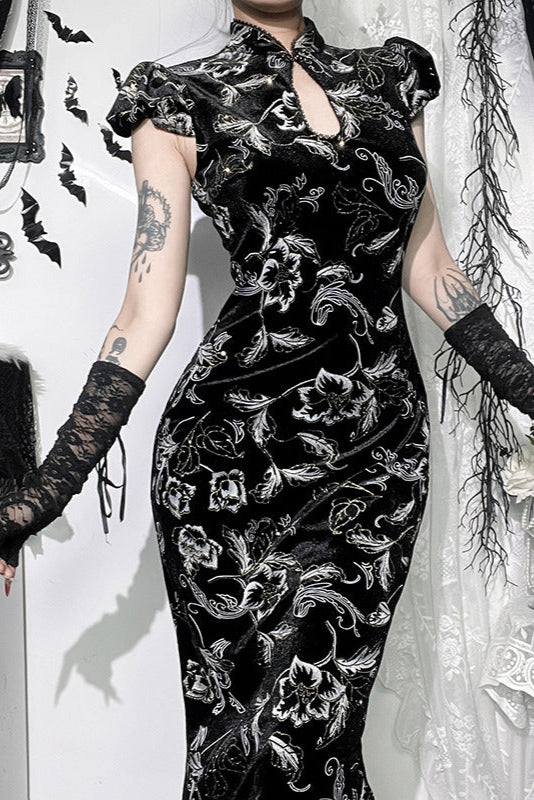 Person wearing a black floral dress with long gloves in a decorative setting.