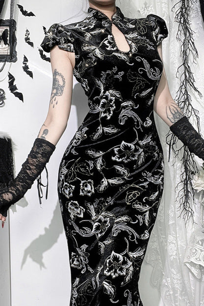Person wearing a black floral dress with long gloves in a decorative setting.