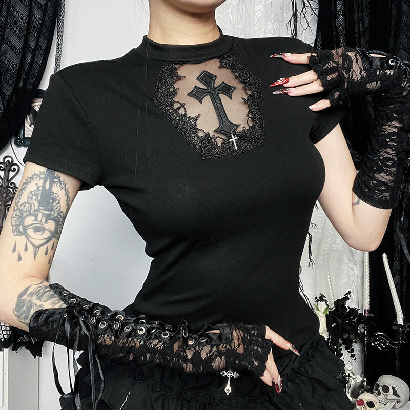Person wearing a black top with lace and cross design, standing against a dark background.