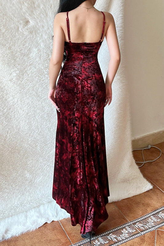 Person wearing a red velvet dress standing against a textured white wall.