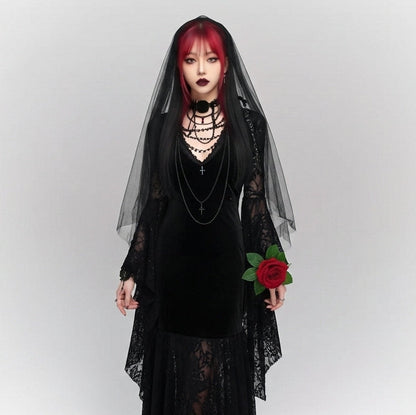 Person wearing a black dress with a sheer overlay and holding a red flower against a white background