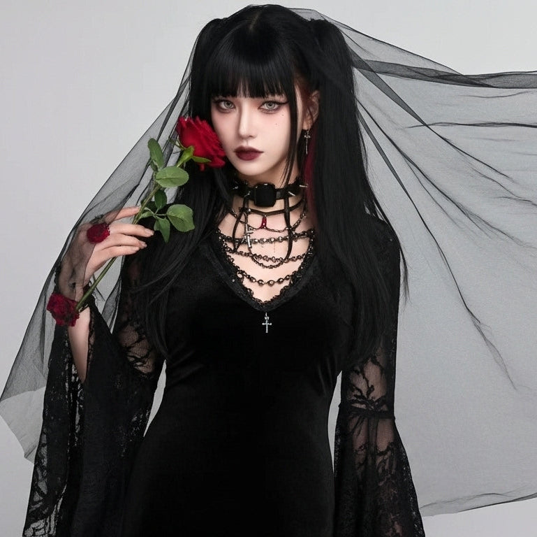 Person in a black dress with sheer sleeves holding a red rose against a gray background