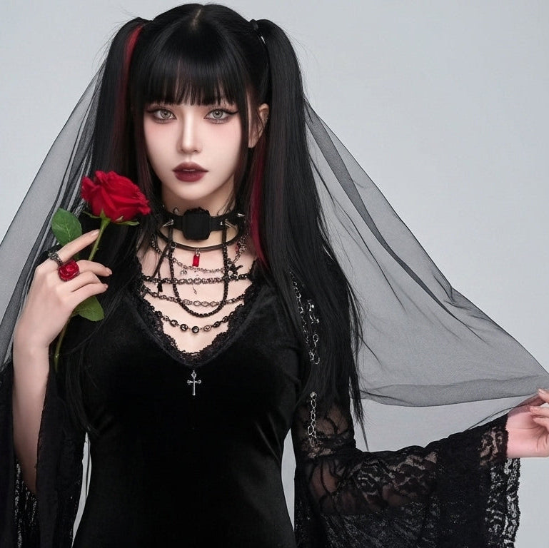 Person in gothic attire holding a red rose against a plain background
